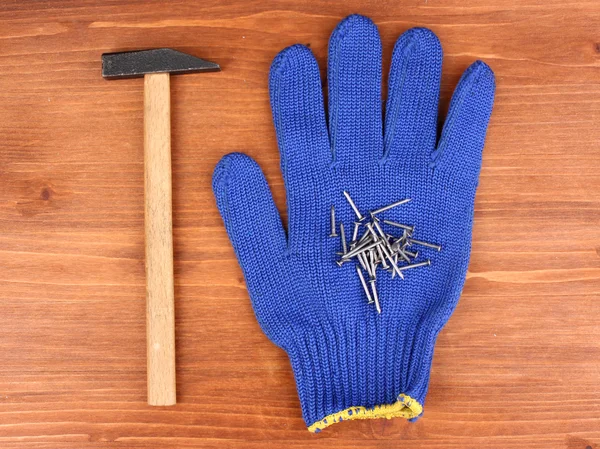 stock image Hammer and glove on wooden background