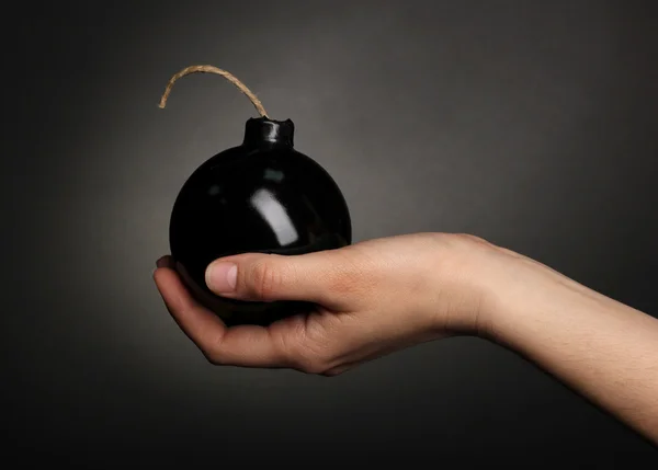 Бомба в стиле мультфильма в руках на черном фоне — стоковое фото
