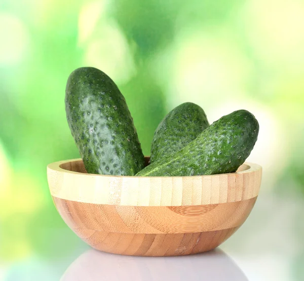 Cucumbers in a wooden bowl on green background — Stock Photo, Image