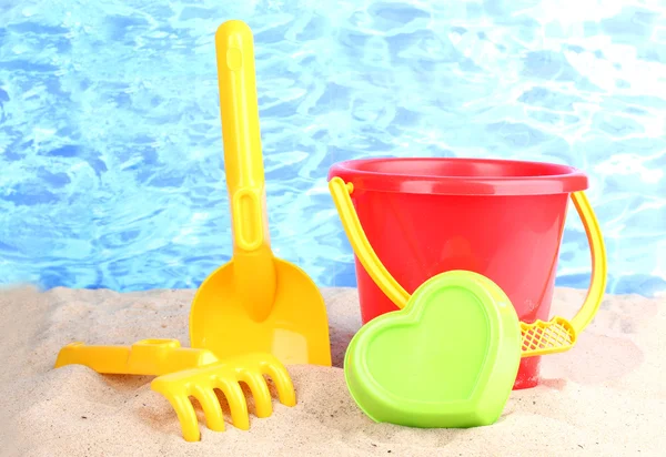 Childrens beach toys on sand on water background — Stock Photo, Image