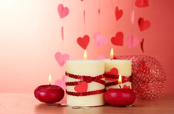 Candles for Valentine's Day on wooden table on red background — Stock Photo, Image