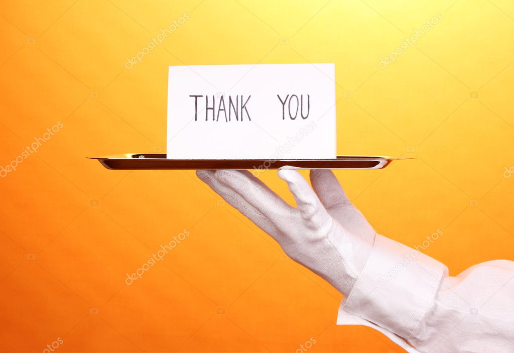 Hand in glove holding silver tray with card saying thank you on yellow background