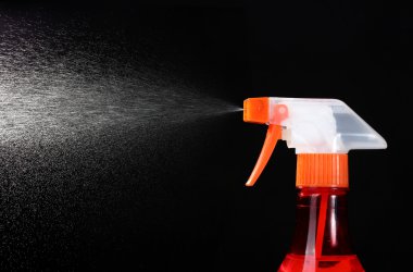 Spray bottle and spraying on black background clipart