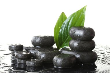 Spa stones with drops and green leaves on white background clipart