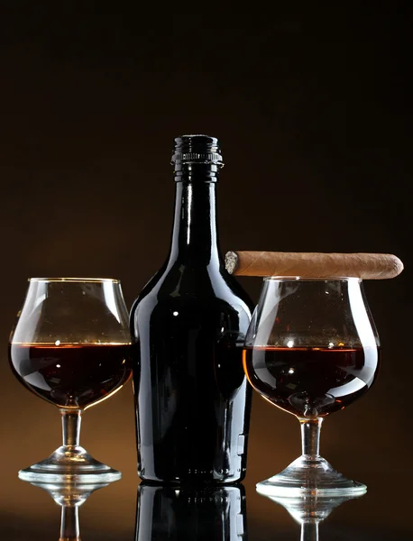 Butelki i puszki z brandy i cygaro na brązowym tle — Zdjęcie stockowe
