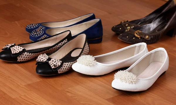 Několik párů ženských plochých bot na dřevěné pozadí — Stock fotografie