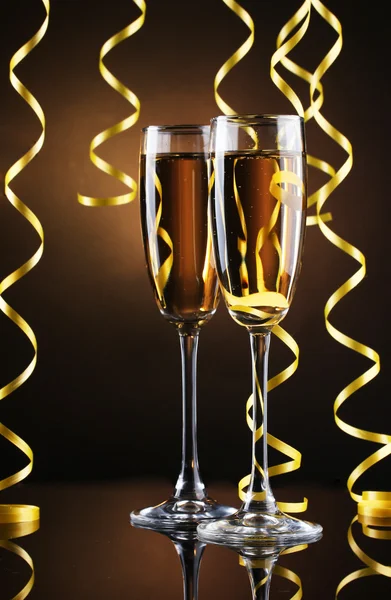 Glazen van champagne en streamer op bruine achtergrond — Stockfoto