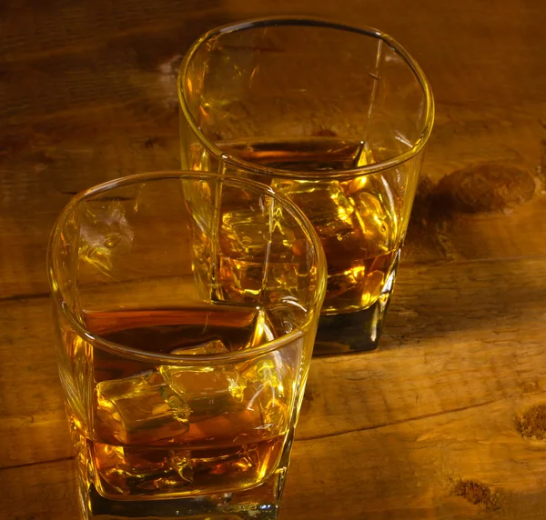 Dos vasos de whisky escocés y hielo sobre mesa de madera —  Fotos de Stock