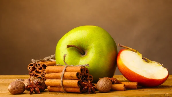 Bastoncini di cannella, mele noce moscata e anice su tavolo di legno su sfondo marrone — Foto Stock