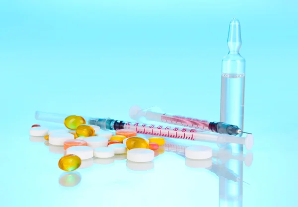 Insulin syringes with medical ampoules and tablets on blue background — Stock Photo, Image