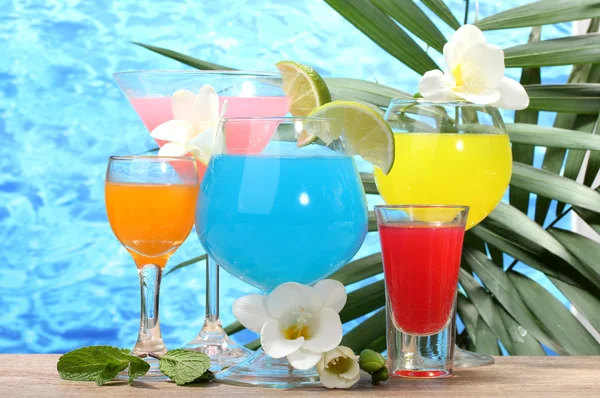 Exotic cocktails and flowers on table on blue sea background — Stock Photo, Image