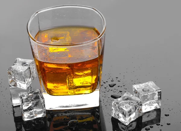 Glas scotch whisky en ijs op grijs tabel — Stockfoto