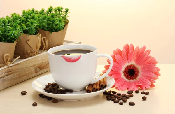 Kopje koffie met lippenstift mark en gerbera bonen, kaneel stokken op houten tafel — Stockfoto