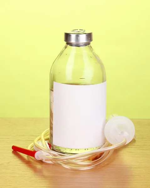 Бутылка внутривенных антибиотиков и пластиковых вливаний на деревянном столе на зеленом фоне — стоковое фото