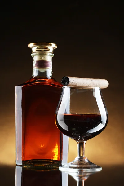 Bottle and glasss of brandy and cigar on brown background — Stock Photo, Image