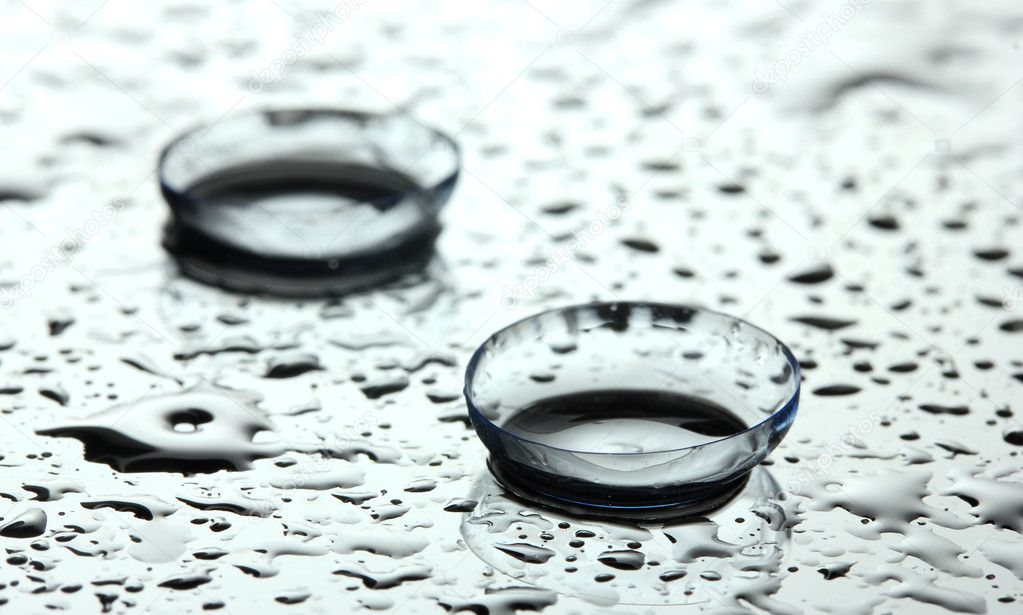 Contact lens with drops on grey background