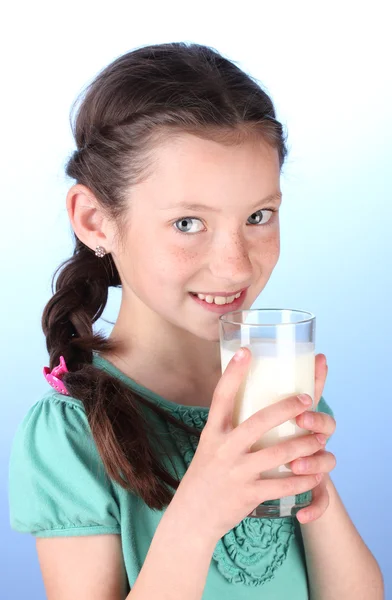 Porträtt av vackra lilla flicka withglass mjölk på blå bakgrund — Stockfoto