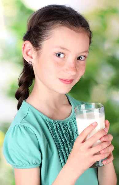 Porträtt av vackra lilla flicka withglass mjölk på grön bakgrund — Stockfoto