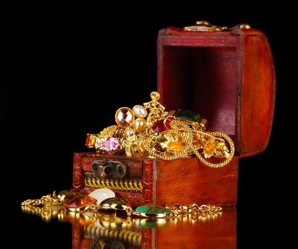 Coffre en bois plein de bijoux en or sur fond noir — Photo