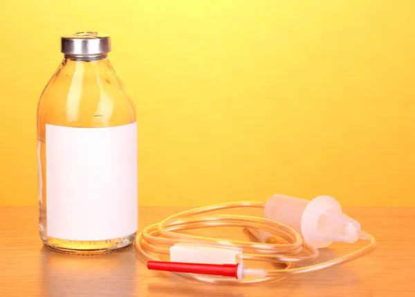 Bottiglia di antibiotici per via endovenosa e infusione di plastica impostata su tavolo di legno su sfondo giallo — Foto Stock