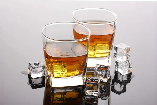 Два стакана виски со льдом на сером столе — стоковое фото