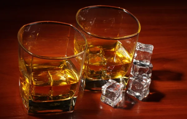 Två glas av skotsk whisky och is på träbord — Stockfoto