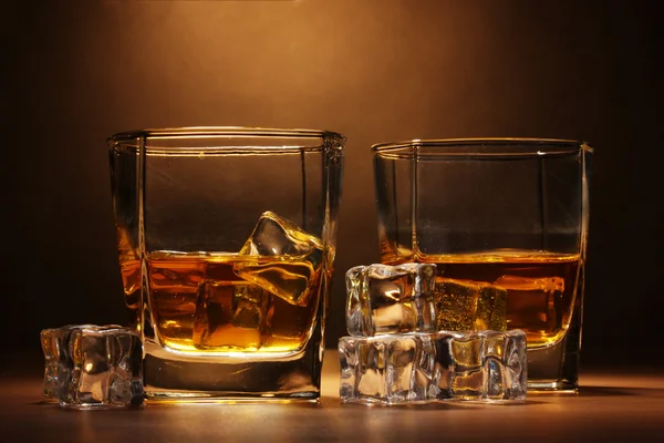 Deux verres de whisky écossais et de glace sur une table en bois sur fond brun — Photo
