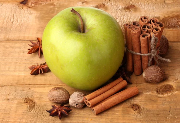 Varas de canela, maçã verde, noz-moscada e anis na mesa de madeira — Fotografia de Stock