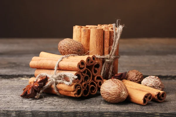 Cinnamon sticks, nutmeg and anise on wooden table on brown background — Stock Photo, Image
