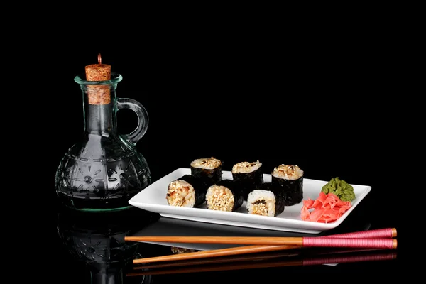 Läckra rullar serveras på vit platta med ätpinnar och sojasås isolerade på svart — Stockfoto