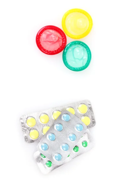 Condones anticonceptivos y pastillas de control aisladas en blanco — Foto de Stock