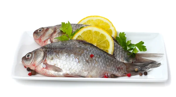 Свежие рыбы с лимоном и петрушкой на тарелке изолированы на белом — стоковое фото
