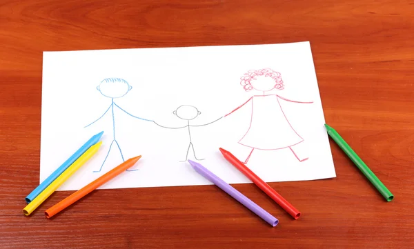 Childrens drawing of family and pencils on wooden background — Stock Photo, Image