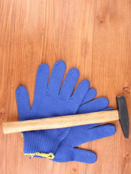 Hammer and gloves on wooden background — Stock Photo, Image