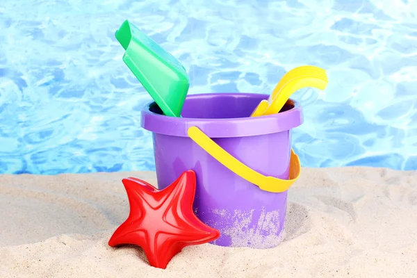 Childrens beach toys on sand on water background — Stock Photo, Image