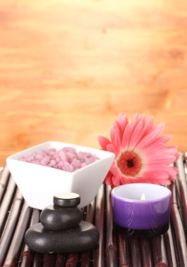 Composition of spa stones, bath salt, candle and gerbera on bamboo mat on wooden background clipart