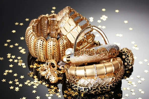 Krásné zlaté šperky na šedém pozadí — Stock fotografie