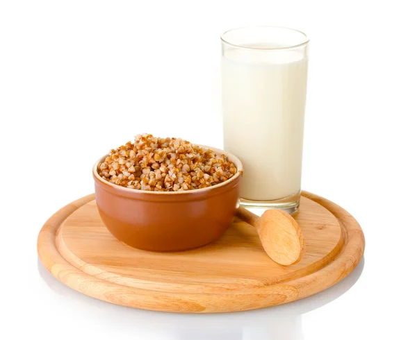 Gekookte boekweit in een bruine kom een glas melk op een houten bord geïsoleerd op wit — Stockfoto