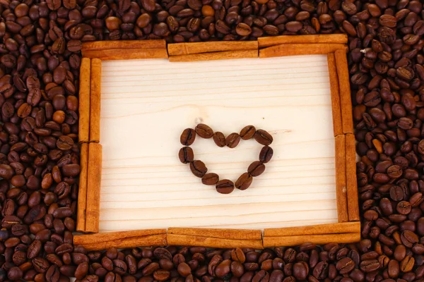 Кадр из кофейных зерен с сердцем на деревянном фоне — стоковое фото
