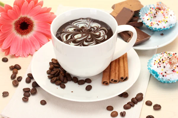 Tasse Kaffee und Gerbera, Bohnen, Zimtstangen auf Holztisch — Stockfoto