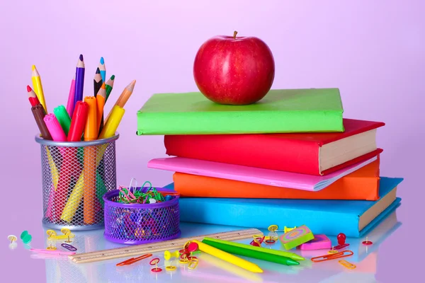 Összetételét könyvek, papíráruk és egy almát, fényes színes háttérrel — Stock Fotó