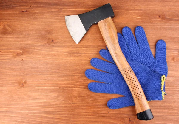 Axe and gloves on wooden background — Stock Photo, Image