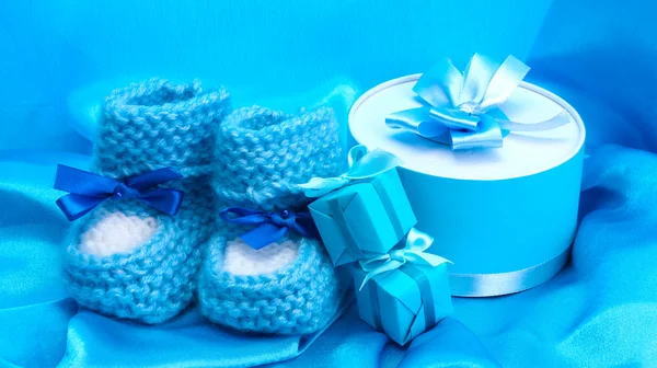 Vackra gåvor och babys stövletter på blå siden — Stockfoto