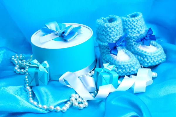 Όμορφα δώρα και babys παντόφλες του μωρού σε μετάξι μπλε — Φωτογραφία Αρχείου