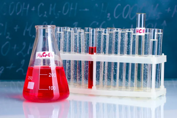 Reagenzgläser mit verschiedenen Säuren und anderen Chemikalien auf dem Hintergrund der Tafel — Stockfoto