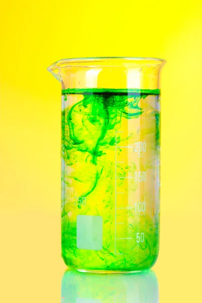 Helder inkt in een kolf met water op gele achtergrond — Stockfoto