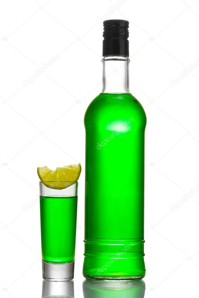 Bottle and glass of absinthe with lime isolated on white