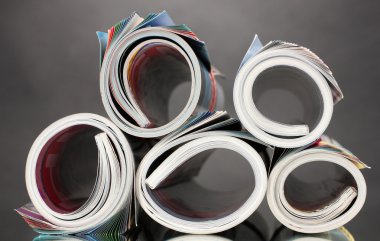 Rolled up magazines on gray background clipart
