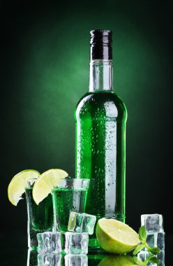 şişe ve bardak pelin yeşil zemin üzerine buz ve limon ile