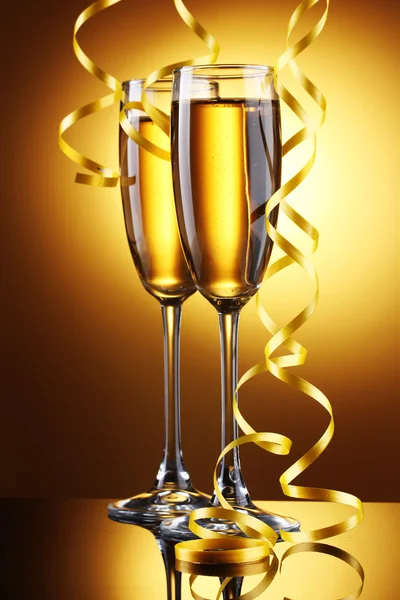 Glas champagne och streamer på gul bakgrund — Stockfoto